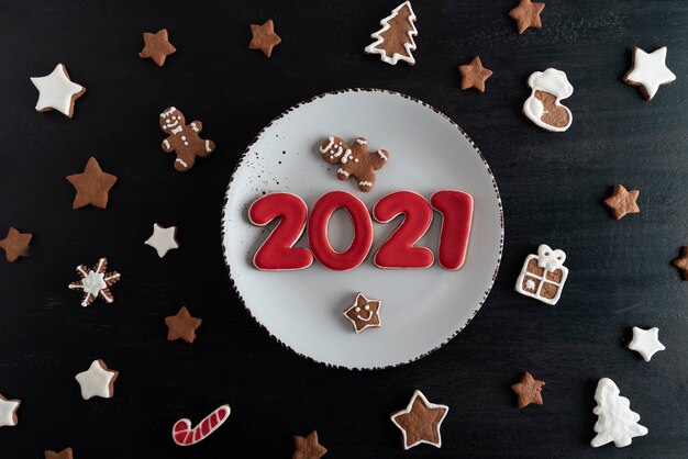 Vista superior Deliciosas galletas pintadas esmaltadas: números 2021, estrellas, abeto.