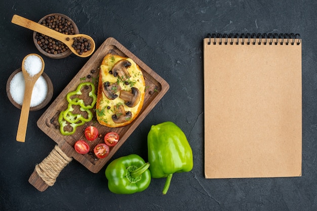 Vista superior de un delicioso refrigerio con verduras frescas de setas y especias cuaderno de espiral sobre fondo negro