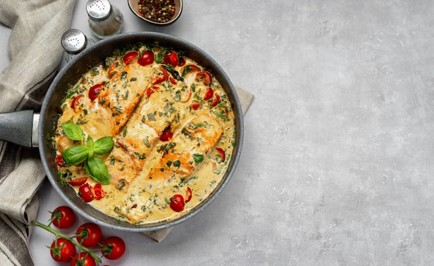 Vista superior del delicioso salmón crema toscana con espinacas en una sartén negra