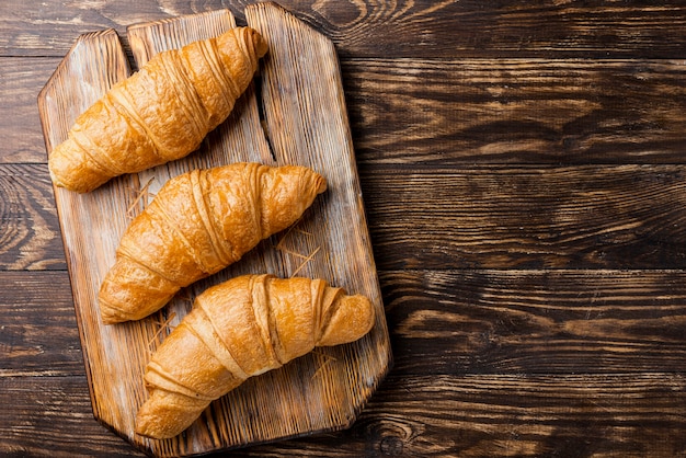 Foto vista superior deliciosos croissants assados na placa de madeira e copie o espaço