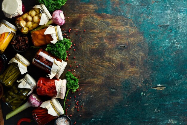 Vista superior de deliciosos encurtidos en frascos Salar varias verduras en frascos de vidrio para almacenamiento a largo plazo Sobre un fondo de piedra negra