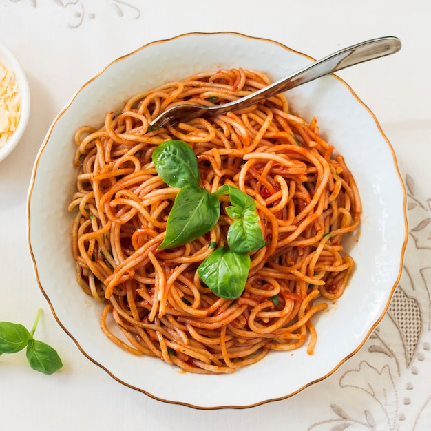 Vista superior de deliciosos espaguetis con albahaca en placa de cerámica