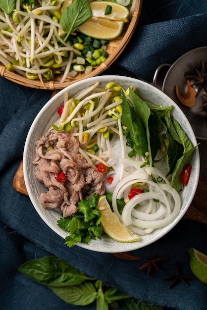 Vista superior de deliciosos fideos de carne vietnamita pho en un recipiente con ingredientes con espacio de copia.