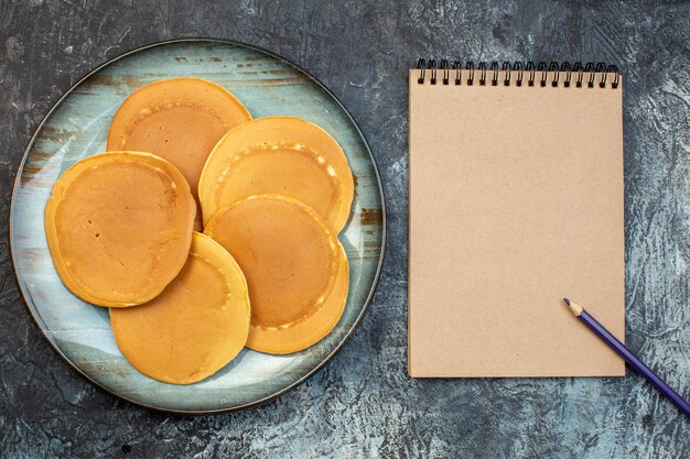 Vista superior deliciosos panqueques con bloc de notas sobre fondo gris miel azúcar desayuno comida de la mañana masa familiar gelatina