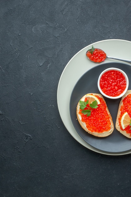 Vista superior deliciosos sándwiches de caviar dentro de la placa sobre una superficie oscura