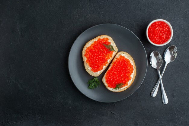 Vista superior deliciosos sándwiches de caviar dentro de la placa sobre una superficie oscura