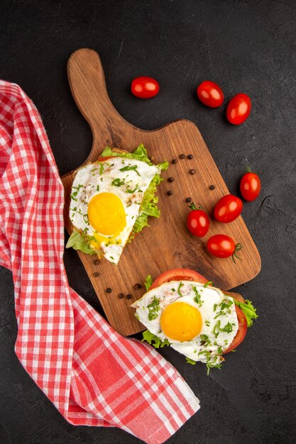 Vista superior deliciosos sándwiches con huevo y tomates sobre fondo oscuro comida pan almuerzo hervir comida desayuno tortilla de huevos