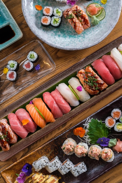 Vista superior de deliciosos sushi y rollos con pescado fresco servido en plato y bandejas en la mesa con salsa de soja