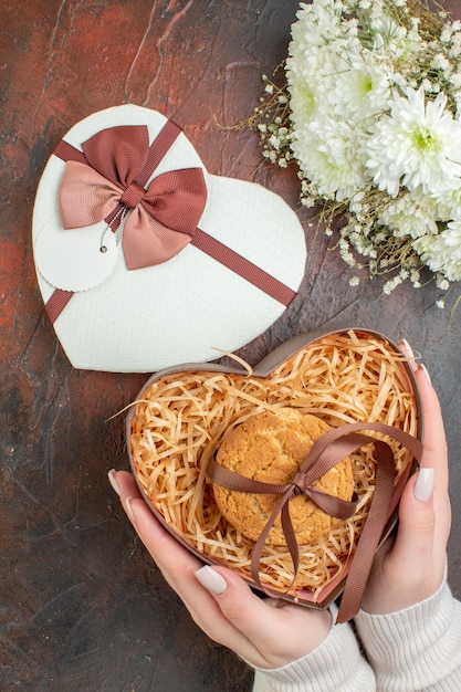 Vista superior día de san valentín presente pequeñas galletas con flores en el fondo marrón oscuro amor color regalo sentimiento matrimonio vacaciones pareja