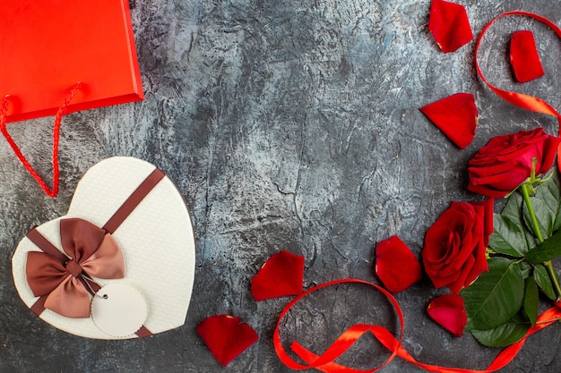 Vista superior del día de San Valentín presente con rosas rojas sobre fondo gris claro pareja matrimonio amor vacaciones corazón pasión