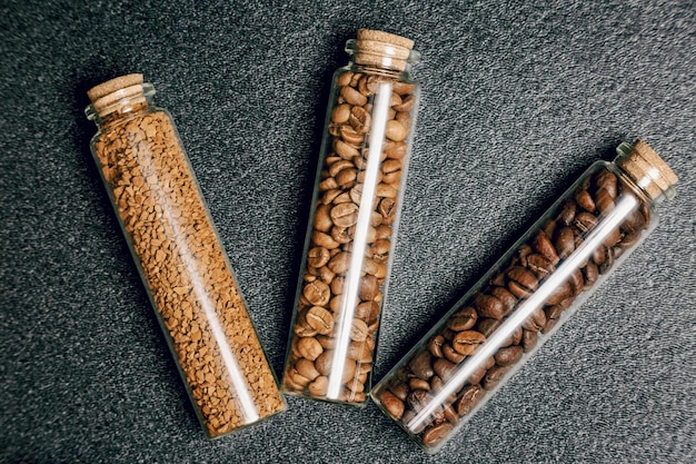 Vista superior de diferentes tipos de granos de café en tres mini botellas de vidrio