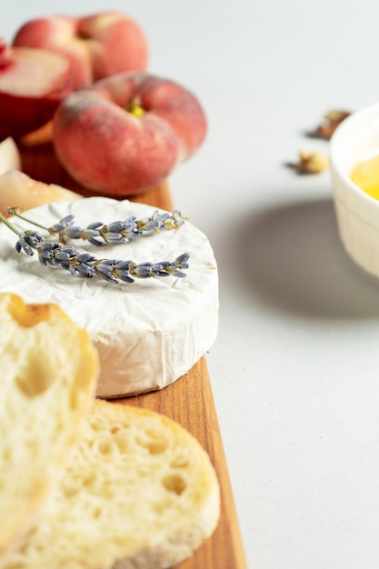 Vista superior de diferentes tipos de quesos en tabla de cortar de madera. Queso con durazno, miel, chapata y nueces, copa de vino tinto. Elegante comida plana yacía sobre fondo gris. Copia espacio Enfoque suave