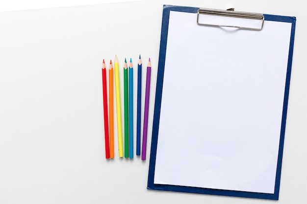 Vista superior Diseño mínimo de cuaderno abierto con lápices de colores del arco iris sobre fondo blanco con espacio en blanco Lay Flat