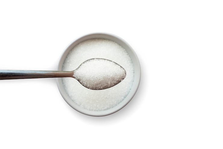 Foto vista superior do açúcar em colheres de chá que estão em uma xícara de açúcar separada em um fundo branco conceito de redução da quantidade de açúcar em alimentos e bebidas.
