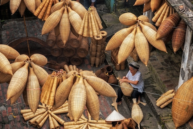 Vista superior do artesão feminino vietnamita, fazendo a armadilha de peixe de bambu tradicional