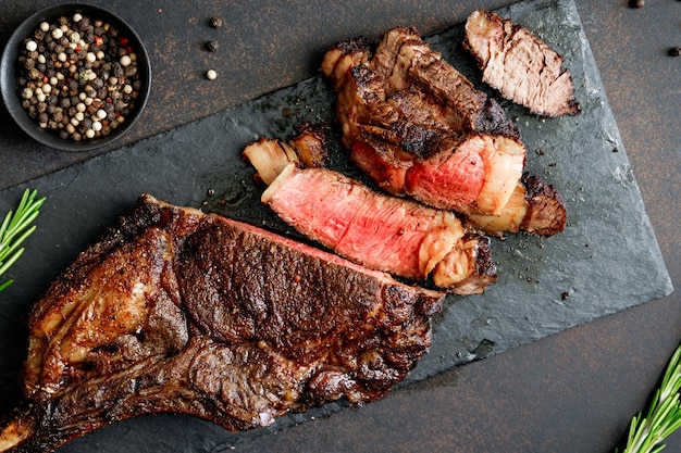 Vista superior do bife de carne seca em mármore Tomahawk em ardósia preta com especiarias Conceito de jantar plano leigo