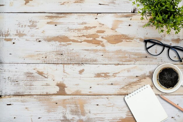 Vista superior do caderno de escola aberta com xícara de café de páginas em branco e lápis para fazer anotações no fundo da mesa