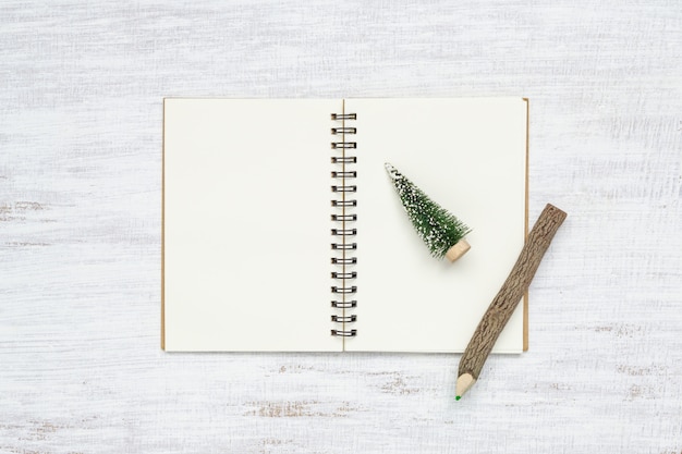 Vista superior do caderno em branco com mini árvore de Natal e lápis