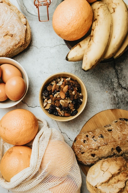 Vista superior do café da manhã saudável com diferentes nozes nozes passas e amêndoas combinadas com bananasoularanjaovos e pão para fazer torradas com omelete Fornecimento de energia vitaminas e proteínas para dieta