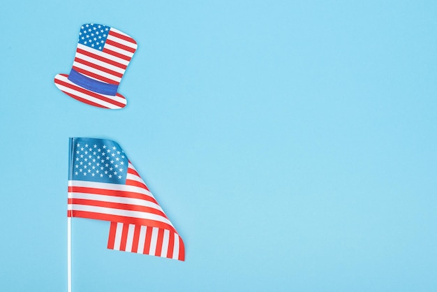 Vista superior do chapéu decorativo de corte de papel feito de bandeira americana perto de estrelas e listras em fundo azul