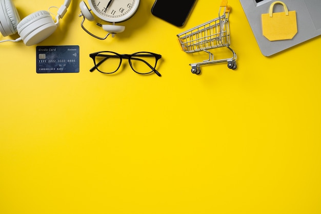 Foto vista superior do conceito de compras online com cartão de crédito, telefone inteligente e computador isolado no fundo da mesa amarela do escritório.