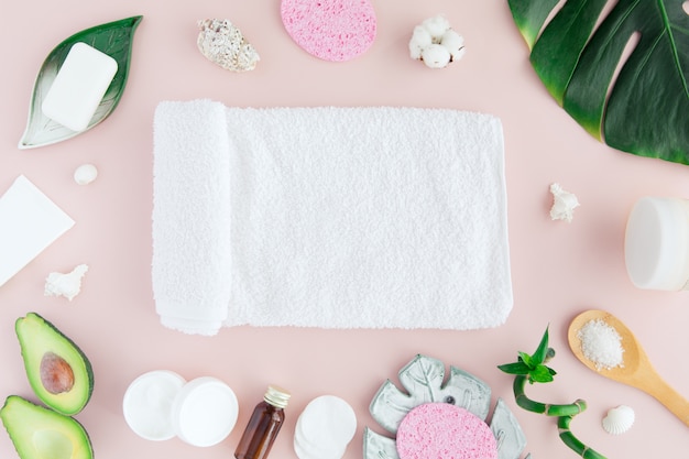 Vista superior do conjunto cosmético branco e verde e folhas para tratamento de spa e cuidados com a pele facial com bambu em rosa