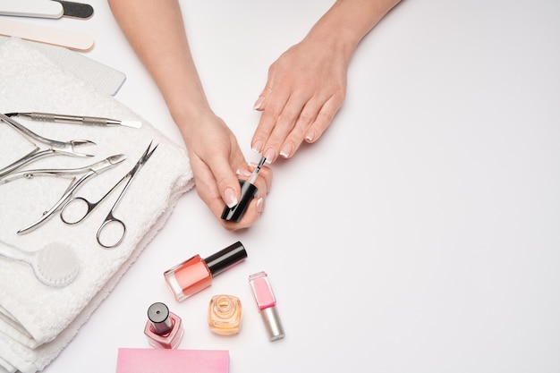 Vista superior do conjunto de ferramentas de manicure para cuidar das unhas sobre uma superfície clara - escova, tesoura, esmalte, lima e pinça