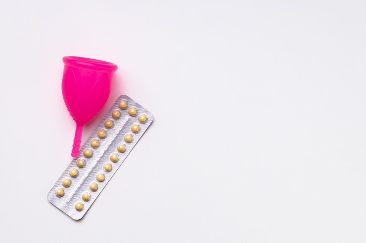 Foto vista superior do copo menstrual e pílulas anticoncepcionais orais