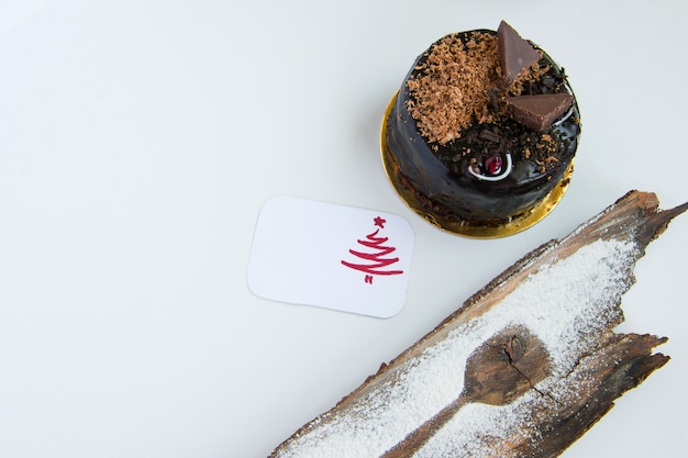 Foto vista superior do delicioso bolo de chocolate de inverno, uma decoração de açúcar de contorno de colher de sobremesa e um cartão de felicitações. fundo branco com espaço para texto