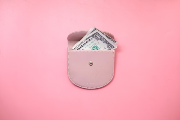 Vista superior do dólar americano em uma carteira em fundo rosa.