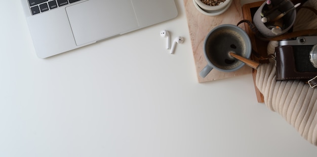 Vista superior do espaço de trabalho confortável com computador portátil e material de escritório em fundo branco de mesa