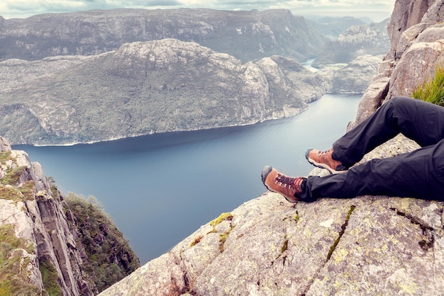 Vista superior do fiorde norueguês com as pernas do turista em primeiro plano