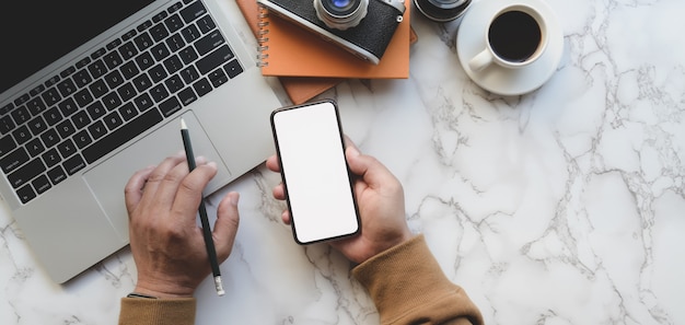 Vista superior do fotógrafo profissional masculino, segurando o smartphone de tela em branco