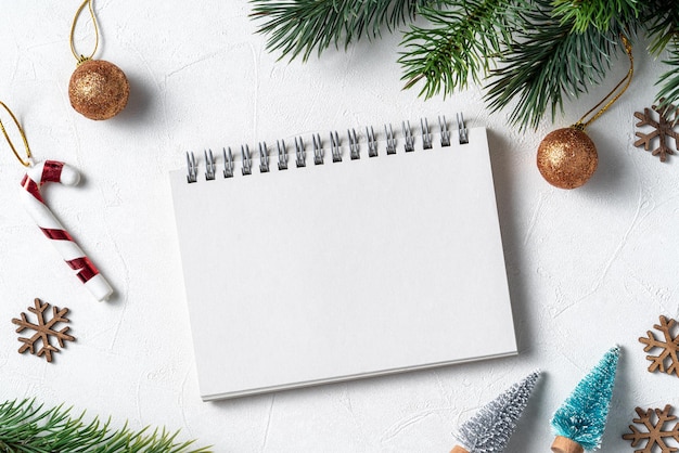 Vista superior do fundo de decorações de natal com caderno em branco sobre fundo de mesa branca com espaço de cópia, conceito de celebração do feriado.