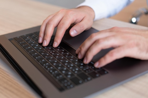 Vista superior do gerente de escritório de mãos masculinas digitando no laptop closeup de mãos de homem no teclado preto Gerente de escritório de homem trabalhando com computador sem rosto Conceito de trabalho