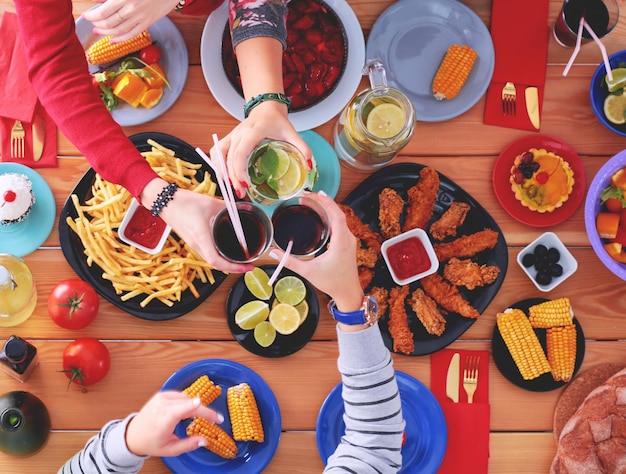 Foto vista superior do grupo de pessoas jantando juntos enquanto estão sentados à mesa de madeira comida na mesa as pessoas comem fast food