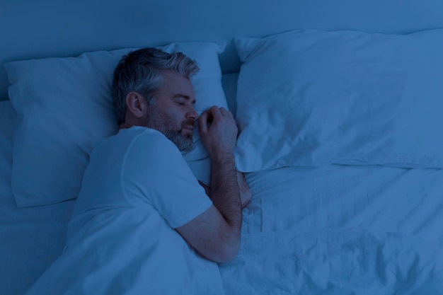 Foto vista superior do homem dormindo sozinho na cama à noite