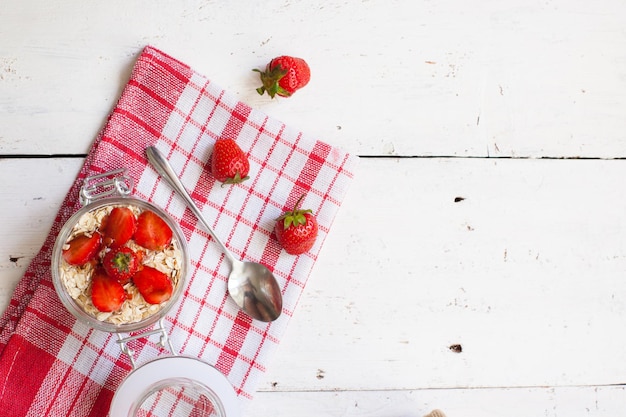 Vista superior do iogurte doce com morangos maduros frescos no café da manhã na velha mesa de madeira com vermelho