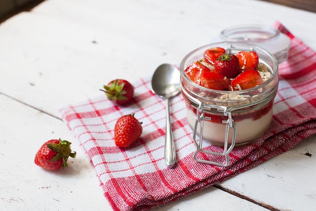 Vista superior do iogurte doce com morangos maduros frescos no café da manhã na velha mesa de madeira