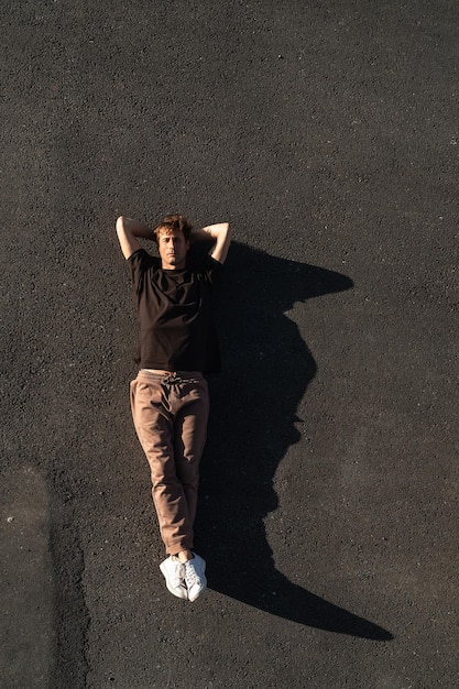 Vista superior do jovem despreocupado deitado no asfalto