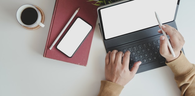 Vista superior do jovem trabalhando em seu projeto com tablet em local de trabalho confortável