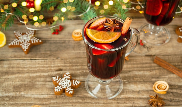 Vista superior do natal quente com vinho quente com cravo, canela, cardamomo e anis em fundo de madeira com decorações de natal