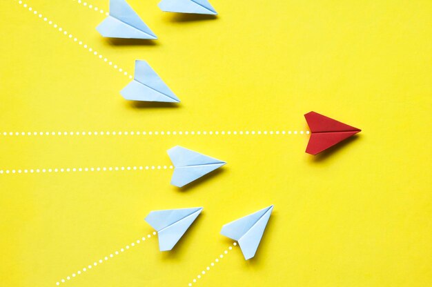 Vista superior do origami de aviões de papel branco perseguindo avião vermelho em fundo amarelo com espaço personalizável para texto ou ideias Conceito de habilidades de liderança e espaço para cópia