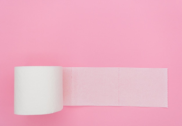 Vista superior do papel higiênico desenrolado no fundo rosa