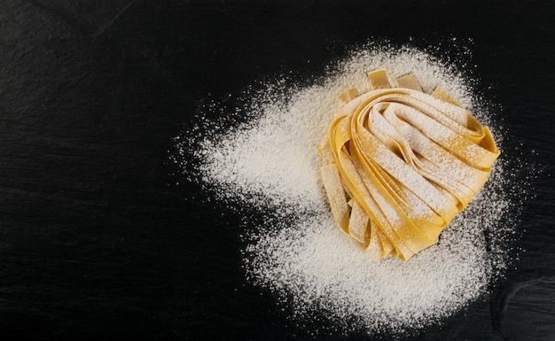 Vista superior do pappardelle, do fettuccine ou do tagliatelle italiano amarelo cru.