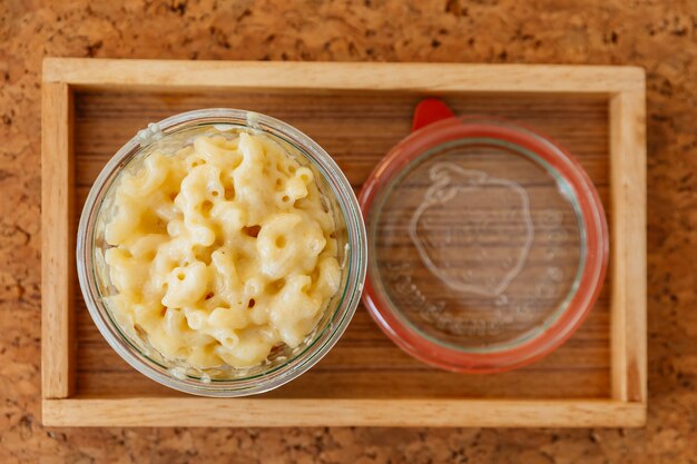 Foto vista superior do queijo de macarrão cozida com molho da carne na bacia de vidro na bandeja de madeira.