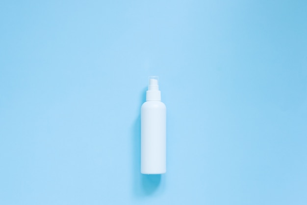 Vista superior do spray anti-séptico antibacteriano em frasco branco para desinfetante de mãos sobre fundo azul. Frasco branco do plástico da bomba do distribuidor do pulverizador do cosmético ou da higiene. Proteção contra vírus. Copie o espaço.