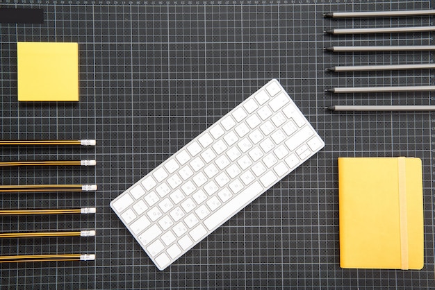 Vista superior do teclado branco e material de escritório organizado em preto