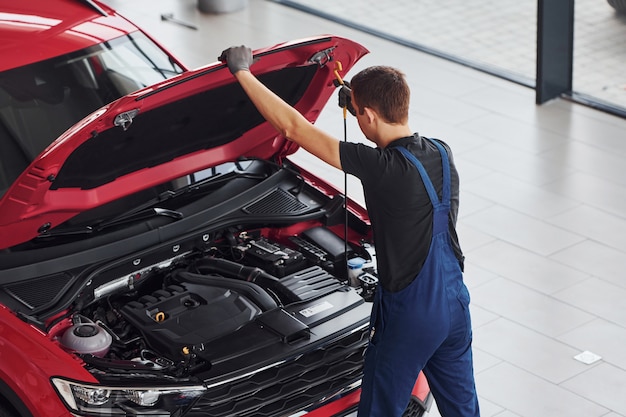 Foto vista superior do trabalhador masculino de uniforme que repara automóvel vermelho