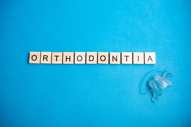 Vista superior dos blocos do alfabeto com letras em um fundo azul. ortodontia - letras. letras e aparelhos ortodônticos para a fileira superior dos dentes